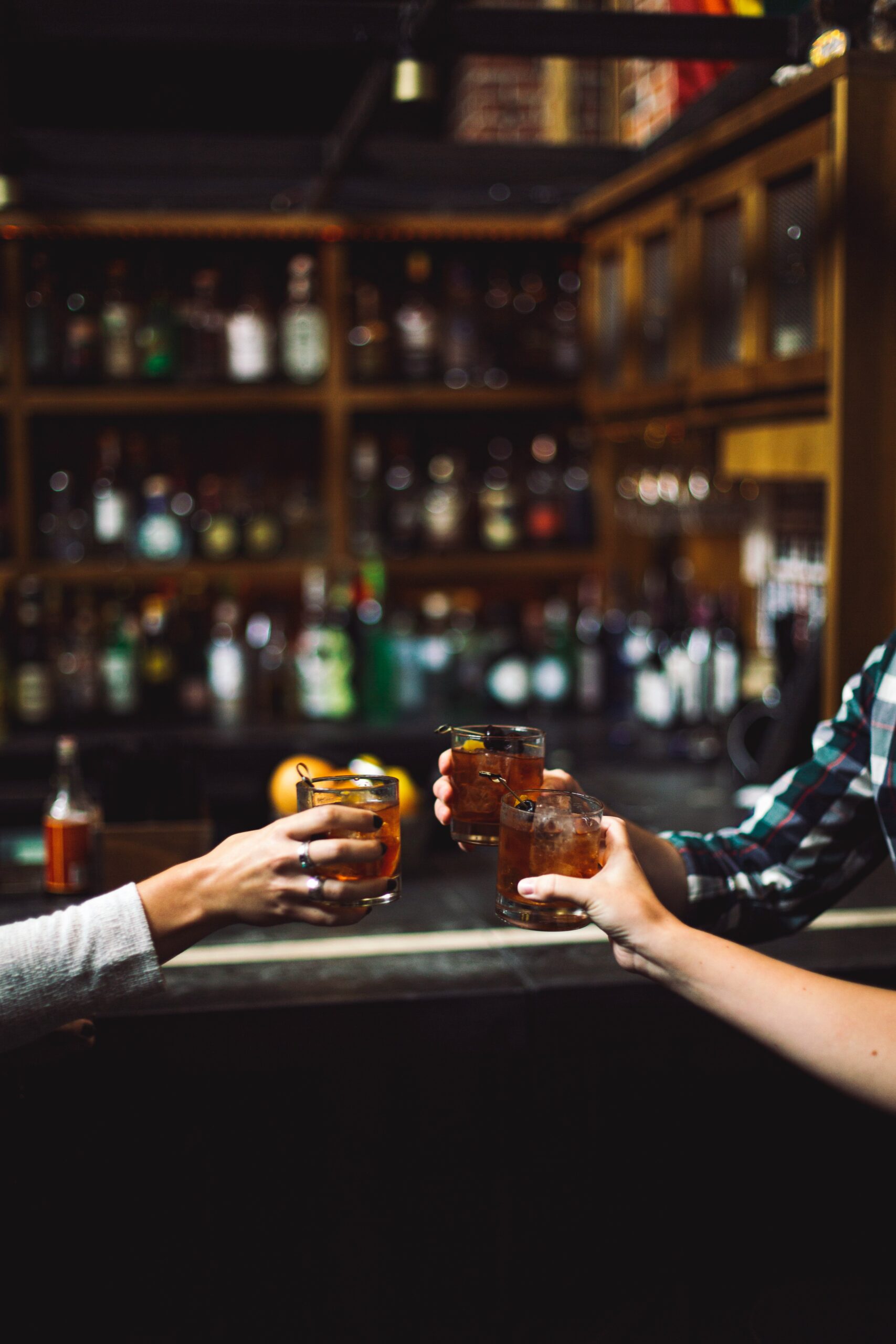 Dimly lit Stockholm bar with blurred bottles and a man alone at the counter