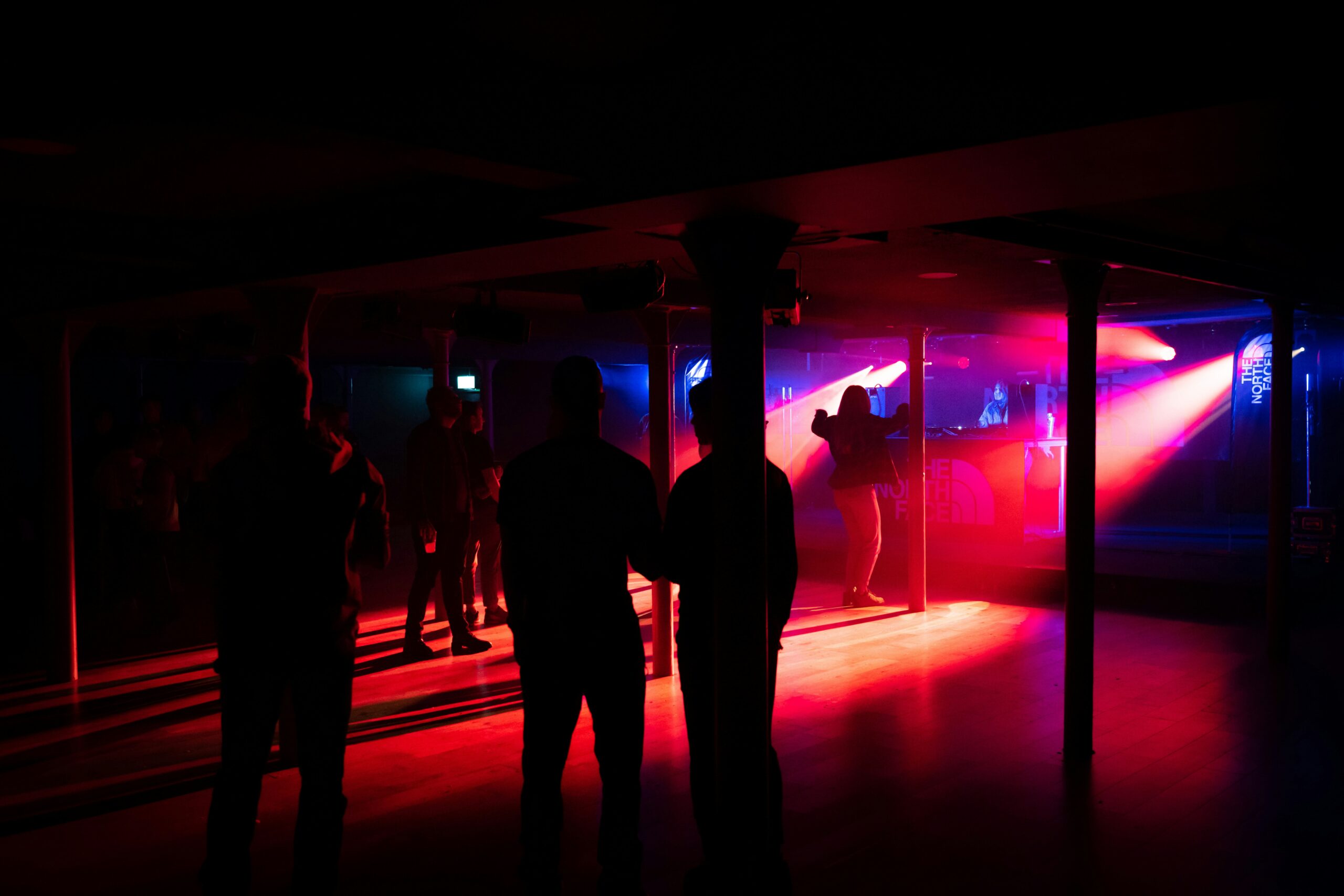 A dimly lit entrance to a discreet club in Stockholm, with rain-slicked streets and soft neon glow reflecting on wet pavement